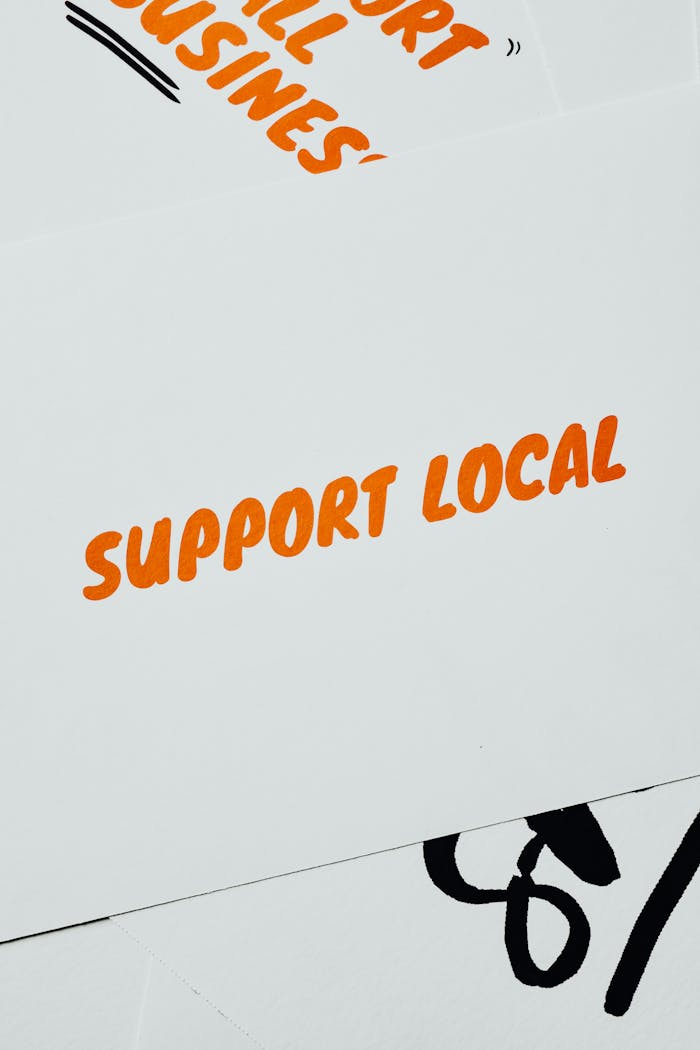 A minimalist card displaying Support Local in bold orange text on a white background, promoting small businesses.